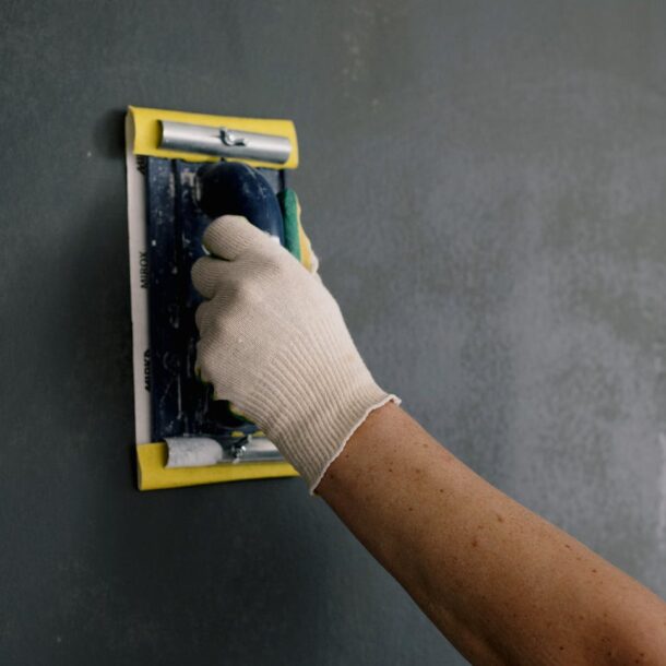 Close-up of a hand smoothing a wall with a spackle tool during home renovation