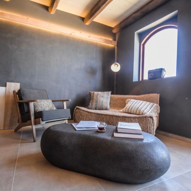 Cozy indoor lounge in Greece with modern rustic design and minimalist decor, featuring a comfortable chair and cozy sofa.