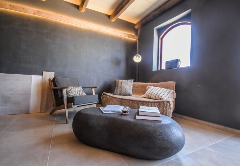 Cozy indoor lounge in Greece with modern rustic design and minimalist decor, featuring a comfortable chair and cozy sofa.