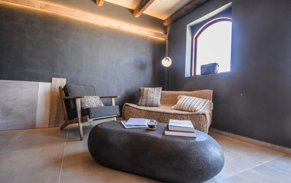 Cozy indoor lounge in Greece with modern rustic design and minimalist decor, featuring a comfortable chair and cozy sofa.