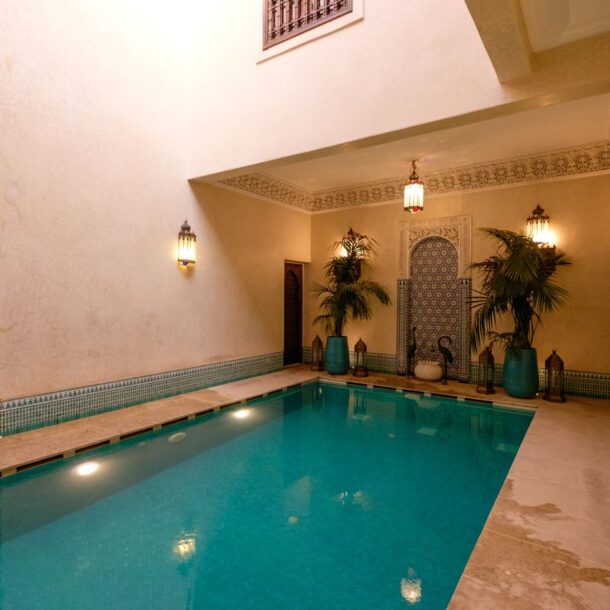 Elegant indoor pool in a Marrakesh riad, showcasing traditional Moroccan architecture and decor.