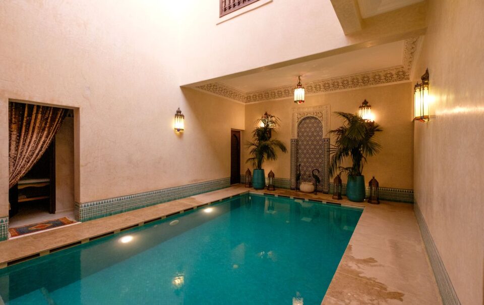 Elegant indoor pool in a Marrakesh riad, showcasing traditional Moroccan architecture and decor.
